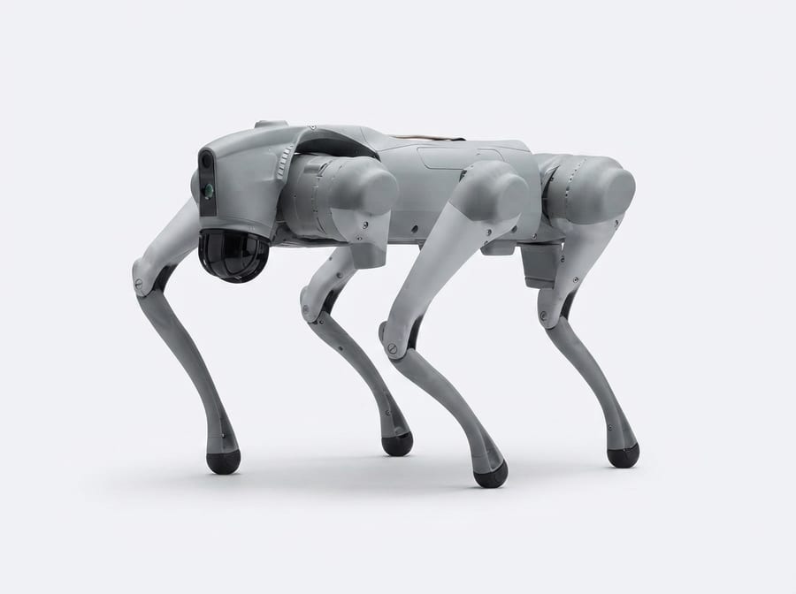 Unitree Go2 in Seitenansicht — grauer Roboterhund mit schwarzer Sensor-Kuppel (KI-Studio-Darstellung nach CC-BY-Fotoreferenz)